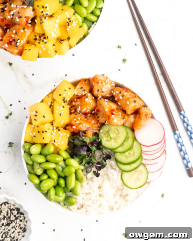 Crispy pieces of chicken covered in a homemade sweet chili sauce are accompanied by mango, cucumber, edamame, radishes, and jasmine rice