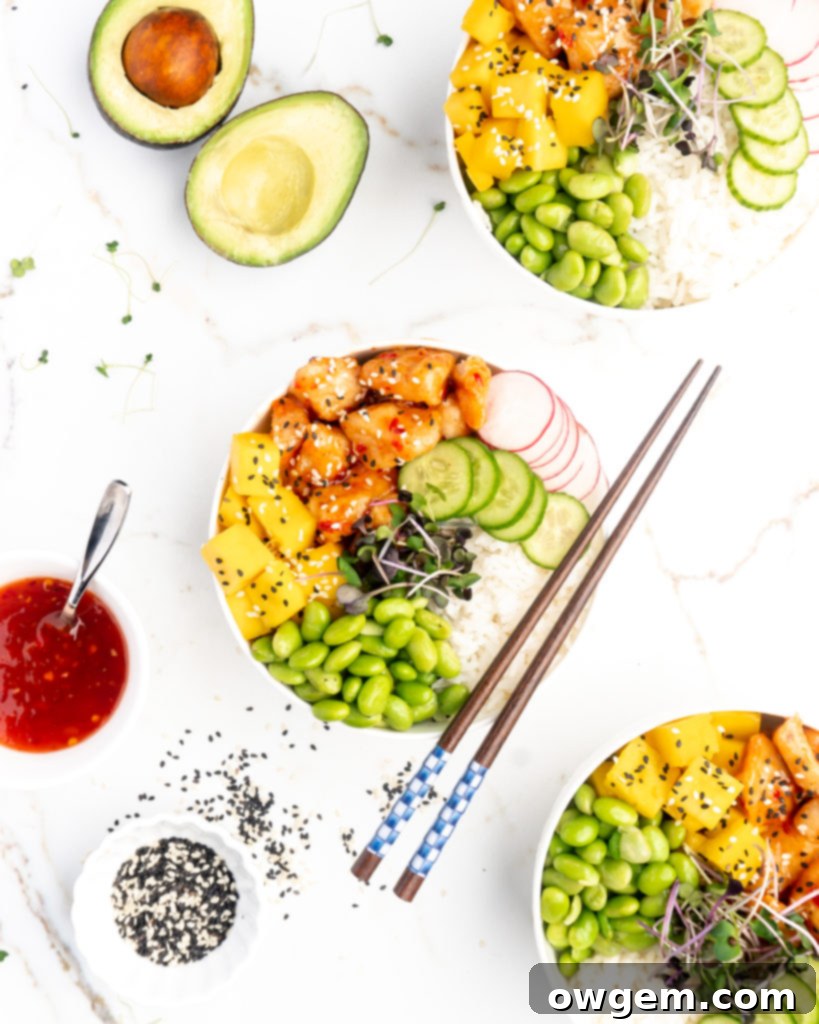 Crispy pieces of chicken covered in a homemade sweet chili sauce are accompanied by mango, cucumber, edamame, radishes, and jasmine rice