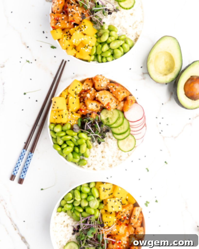 Crispy pieces of chicken covered in a homemade sweet chili sauce are accompanied by mango, cucumber, edamame, radishes, and jasmine rice