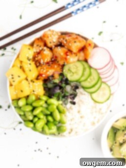 Crispy pieces of chicken covered in a homemade sweet chili sauce are accompanied by mango, cucumber, edamame, radishes, and jasmine rice