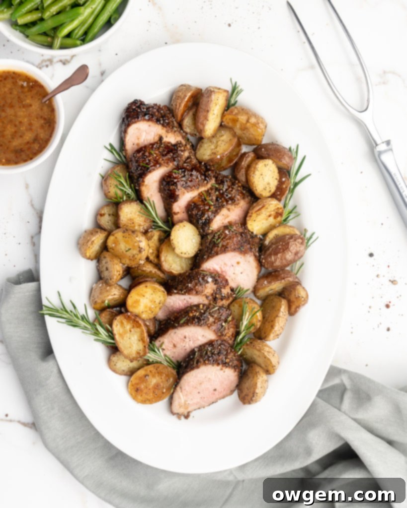 Slices of juicy rosemary peach mustard glazed pork tenderloin served on a plate with fresh rosemary.