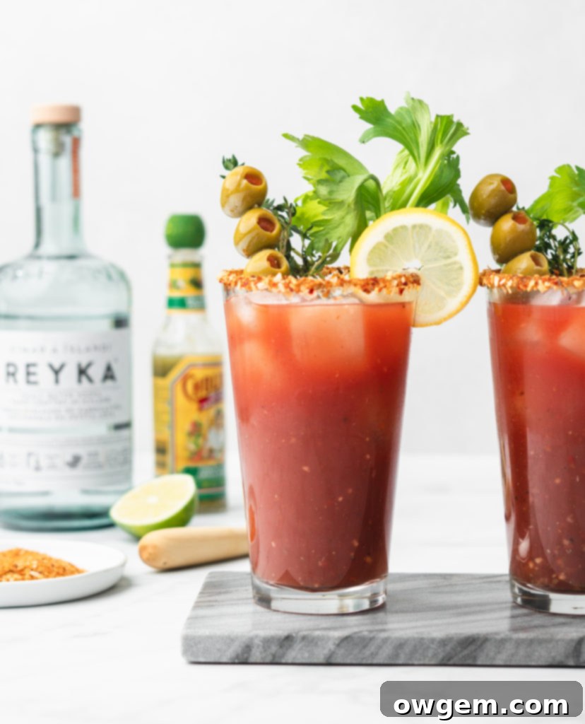 HP sauce, worcestershire sauce, pickle juice, horseradish, tobasco, and seasonings come together with vodka and clamato to make the Best Caesar recipe! A vibrant red cocktail garnished with a lime wedge and a celery stick.