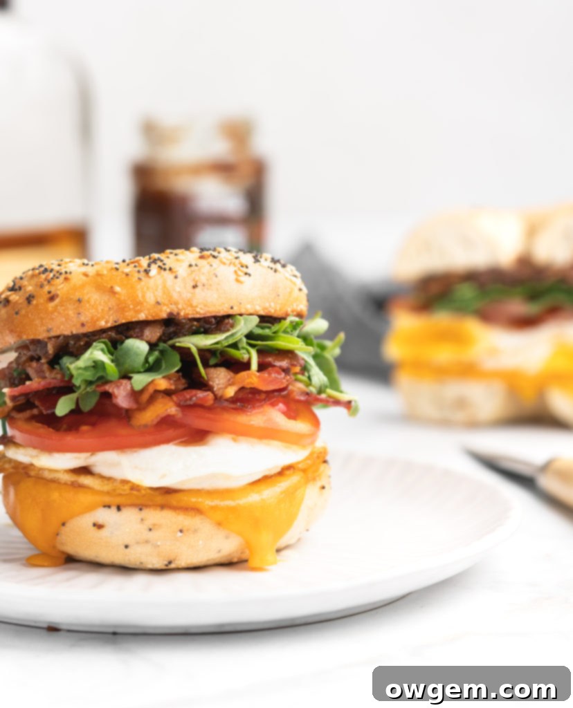 This bagel breakfast sandwich features cheddar, a fried egg, crispy bacon, juicy tomatoes, peppery arugula, sweet apple chutney, and savory bacon jam, all sandwiched between a garlicky everything bagel