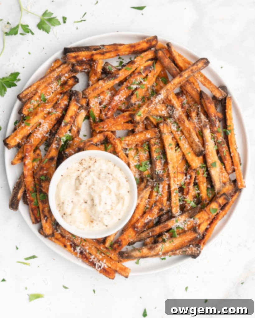 Crispy oven baked sweet potato fries topped with finely shredded parmesan cheese, served with a flavorful homemade truffle lemon aioli