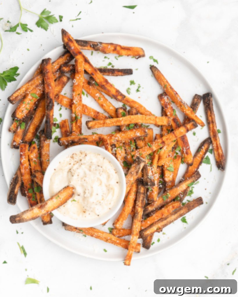Sweet potato fries tossed with oil and garlic powder on a baking sheet