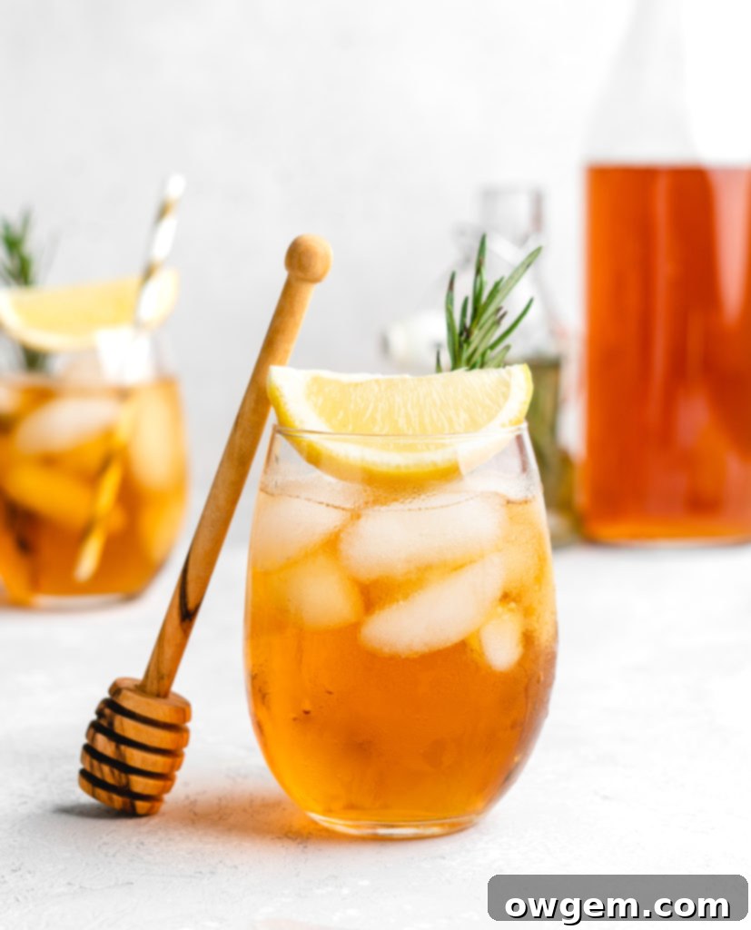 A refreshing glass of Honey Rosemary Iced Tea, sweetened with a homemade rosemary honey simple syrup, garnished with fresh rosemary and lemon.