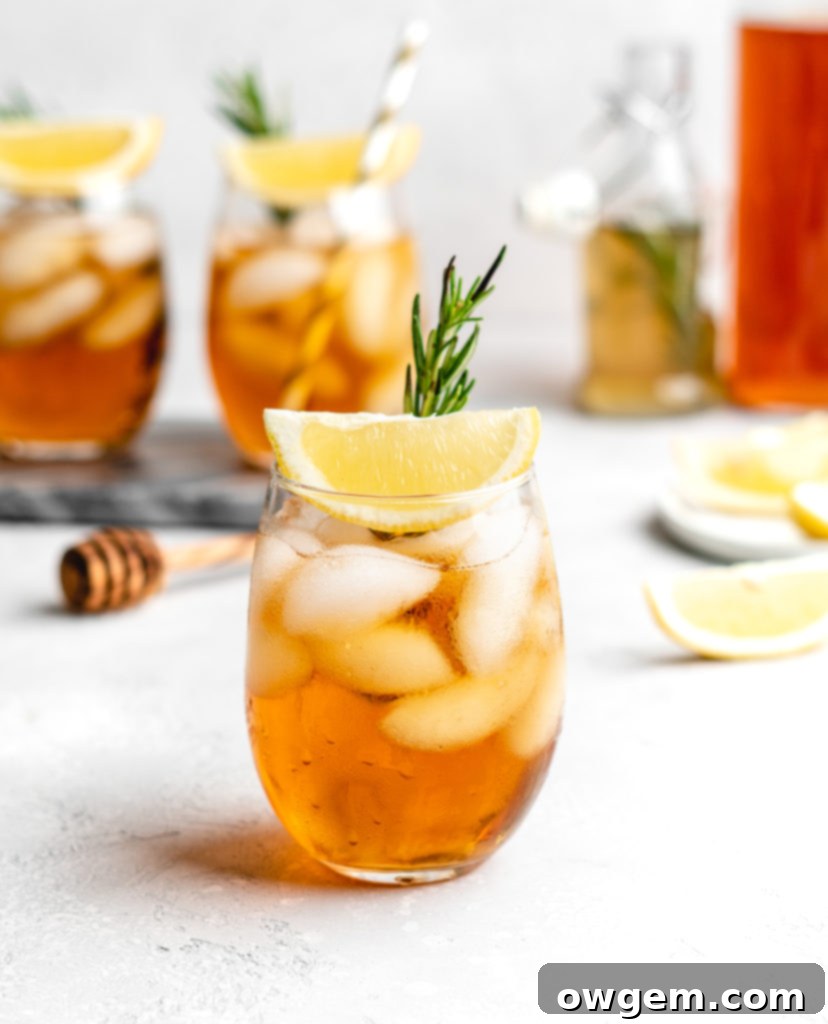A close-up of Honey Rosemary Iced Tea, showing the amber color of the tea and the fresh rosemary sprigs.