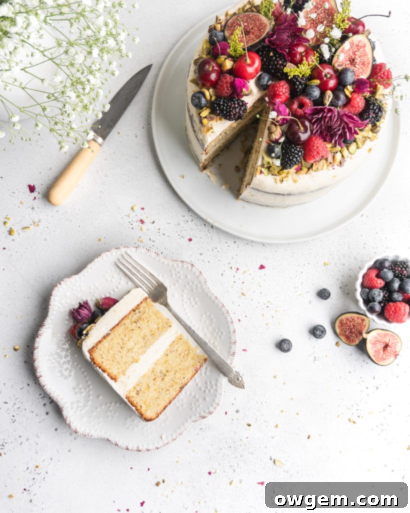 A close-up of a semi-naked Pistachio cake, revealing its moist crumb and delicate honey rosewater buttercream