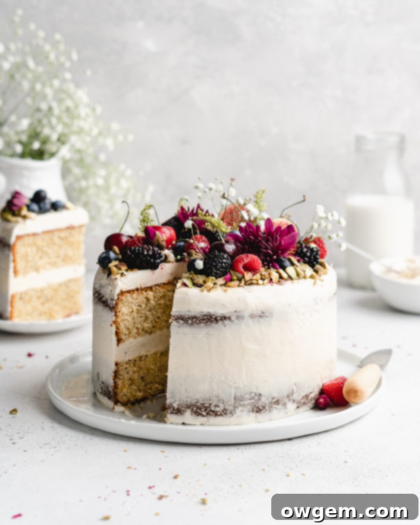 A semi-naked pistachio cake with honey rosewater swiss meringue buttercream, garnished with chopped pistachios and dried rose petals