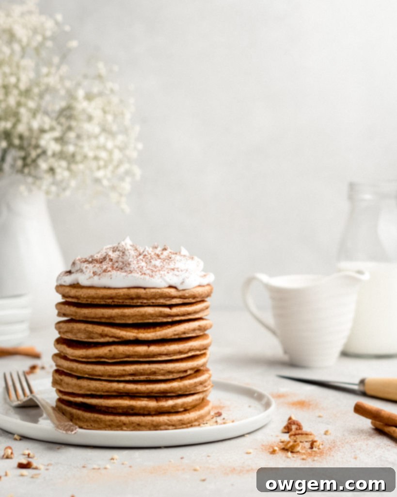 Fluffy Cinnamon Bun Pancakes topped with generous cream cheese frosting, a perfect dessert-like breakfast.