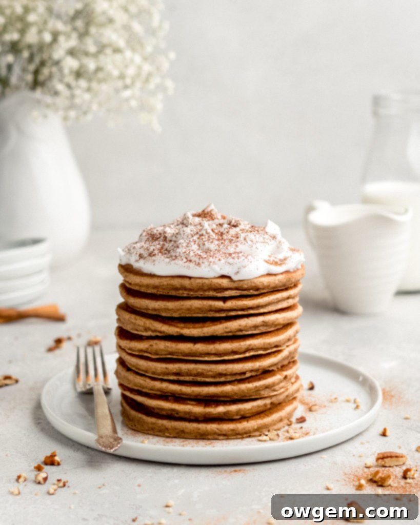 Close-up of golden-brown Cinnamon Bun Pancakes stacked with cream cheese frosting, ready to serve.