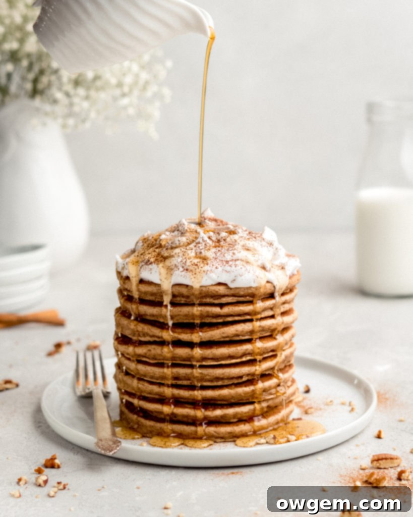 A stack of Cinnamon Bun Pancakes on a griddle, showing the perfect golden-brown finish.