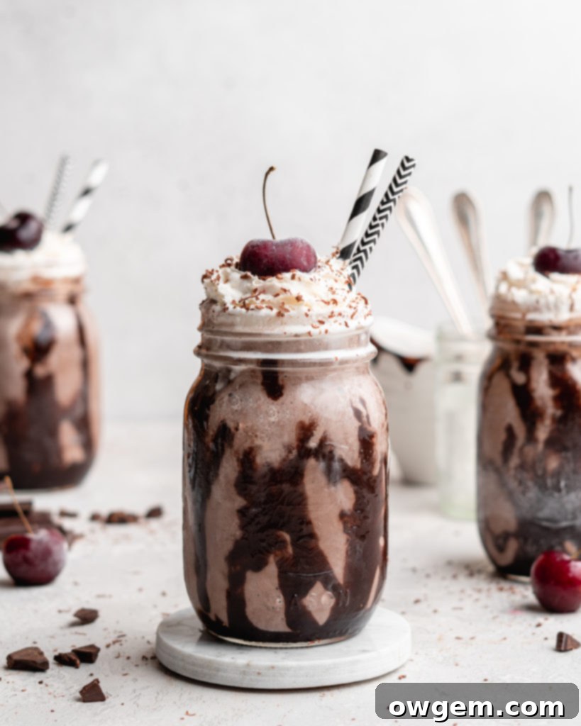 Close-up of a Black Forest Chocolate Cherry Milkshake, highlighting the smooth, thick texture and the vibrant red cherry on top of the whipped cream.