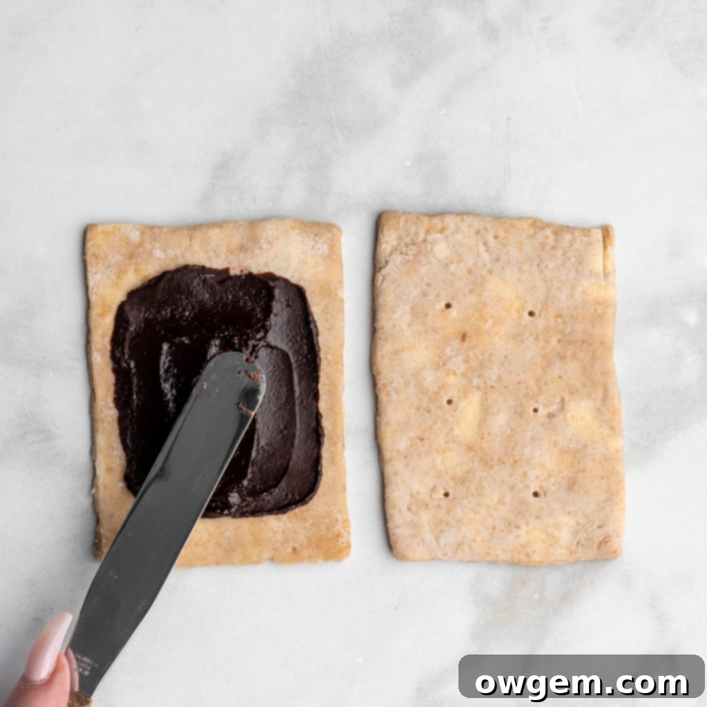 Spread chocolate filling onto the bottom pastry, leaving a 3/4-inch border.