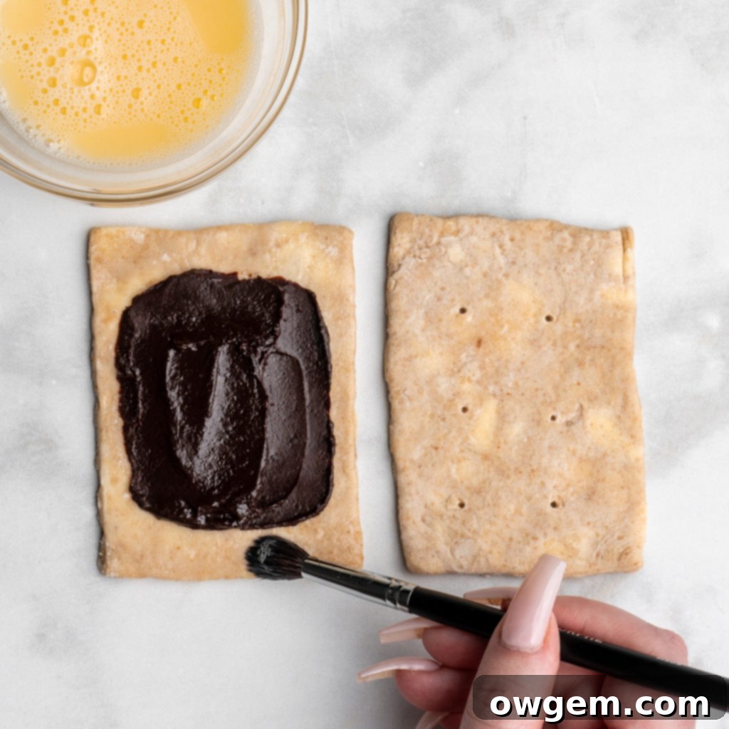 Apply egg wash around the border of the bottom pastry for a secure seal.