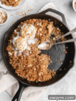 A beautifully plated slice of Maple Cardamom Apple Crisp with a scoop of vanilla ice cream, ready to eat.