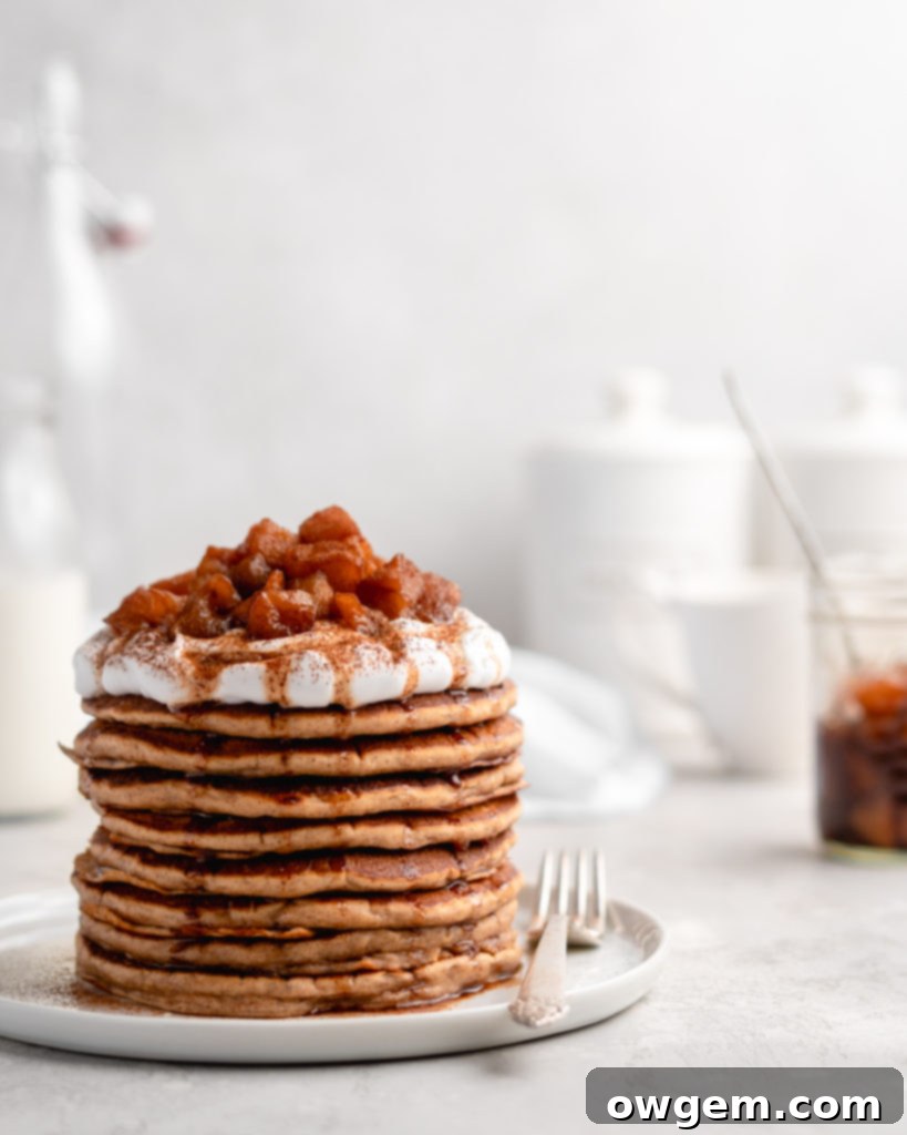 Stack of fluffy apple cinnamon pancakes topped with a delicious homemade apple compote and a drizzle of apple syrup, perfect for breakfast