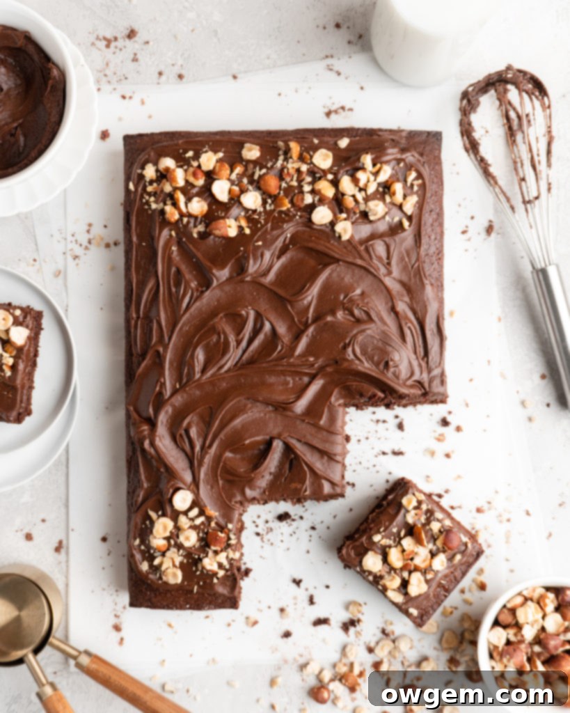 A slice of rich Toasted Hazelnut Chocolate Sheet Cake topped with creamy Nutella frosting, showcasing its moist texture and inviting chocolate-hazelnut aroma.