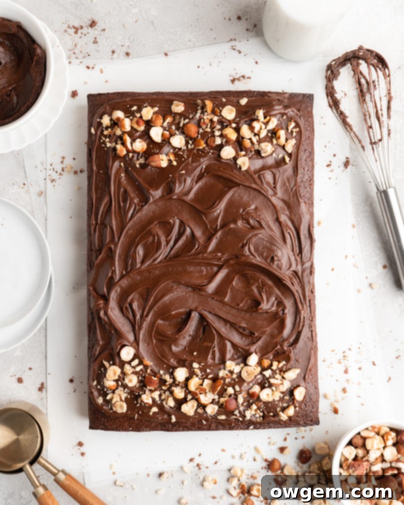 A close-up of a beautifully decorated Toasted Hazelnut Chocolate Sheet Cake with Nutella frosting and a sprinkle of chopped hazelnuts.
