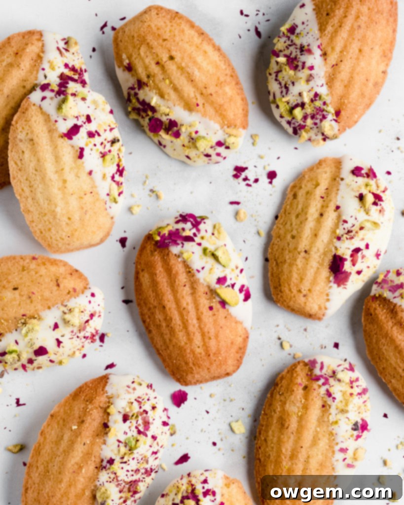 Pistachio Rosewater Madeleines being dipped into melted white chocolate.