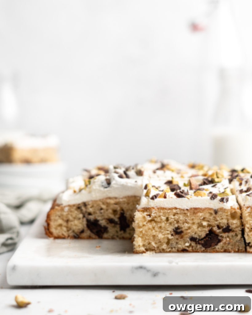 A vibrant, close-up image of the Cannoli Cake, showcasing the pistachios and chocolate on top, ready to be enjoyed.