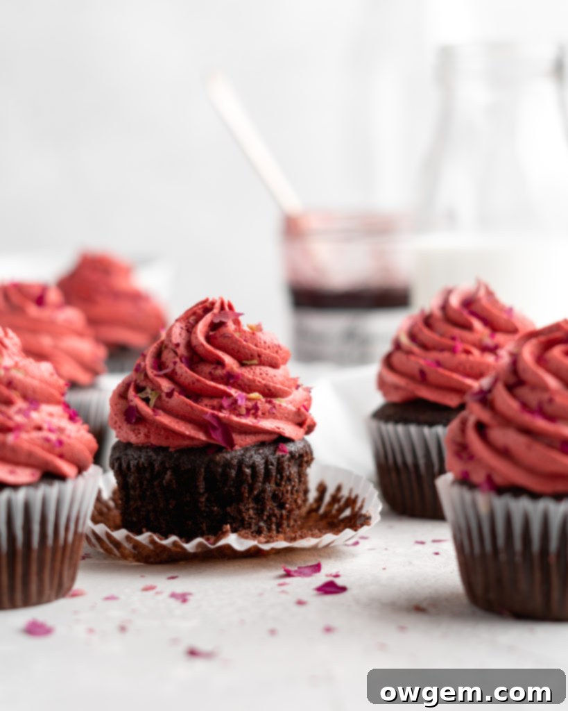 Two chocolate cherry cupcakes, one showing the jam filling before frosting, highlighting the ease of preparation