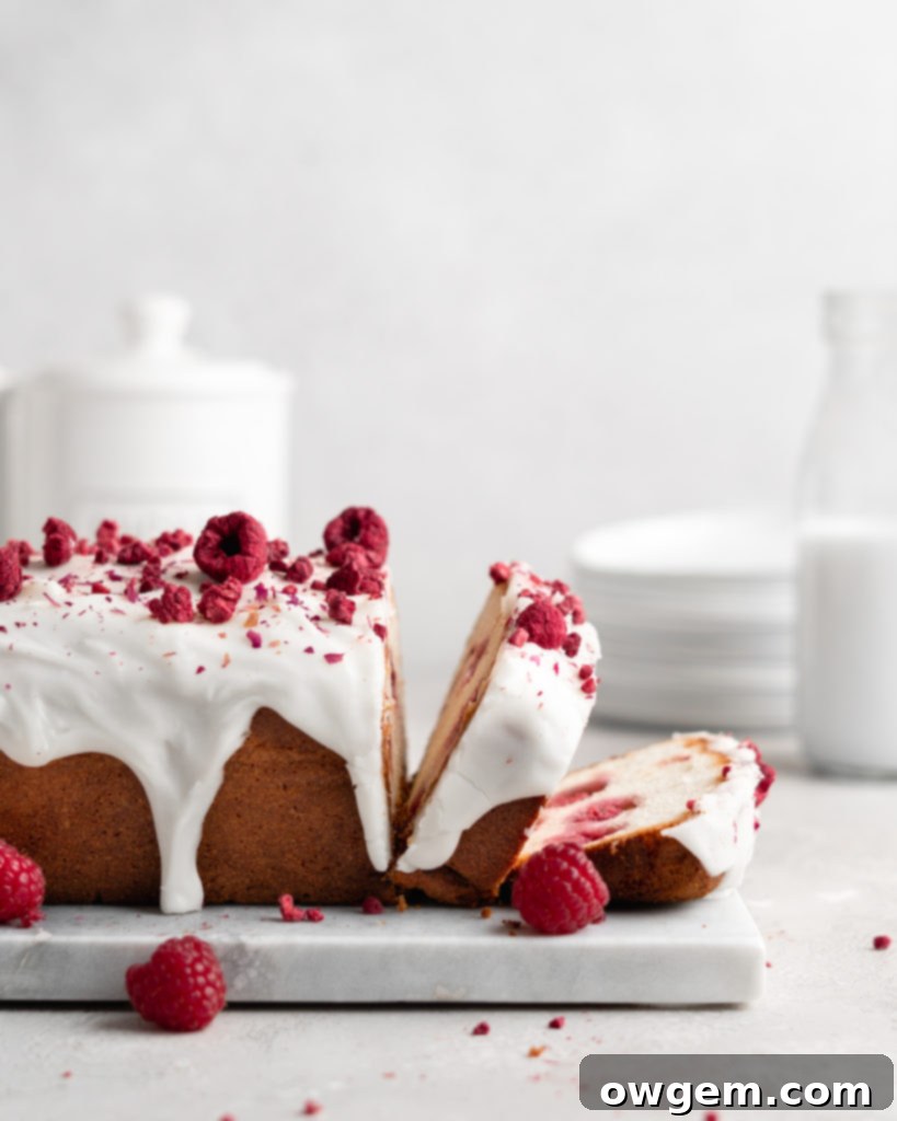 A beautifully glazed loaf cake, speckled with fresh raspberries and adorned with edible rose petals, reflecting the delicate rosewater flavor and moist texture.