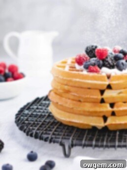 A stack of golden brown Buttermilk Belgian Waffles on a white plate, ready to be topped