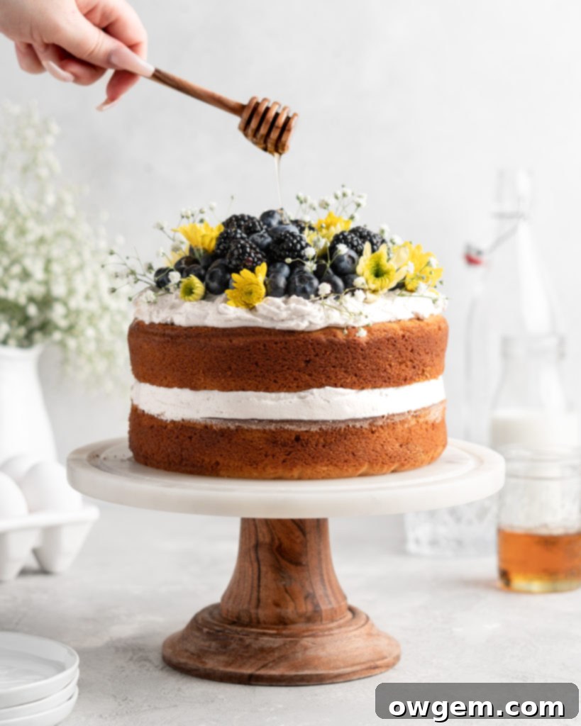 2 layer naked styled chamomile and honey infused cake is decorated with berries and flowers