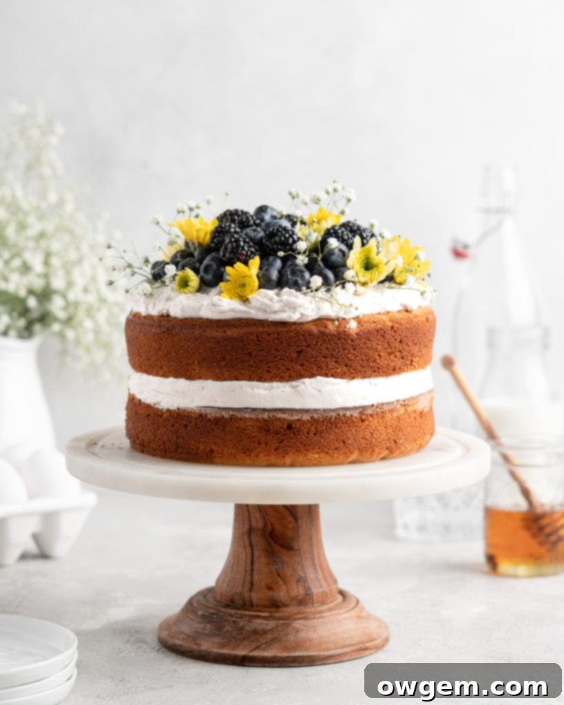 2 layer naked styled chamomile and honey infused cake is decorated with berries and flowers