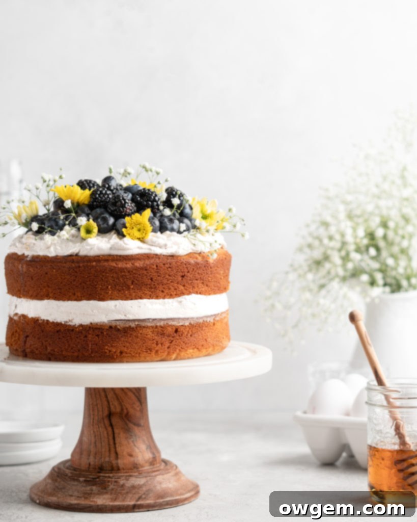 2 layer naked styled chamomile and honey infused cake is decorated with berries and flowers