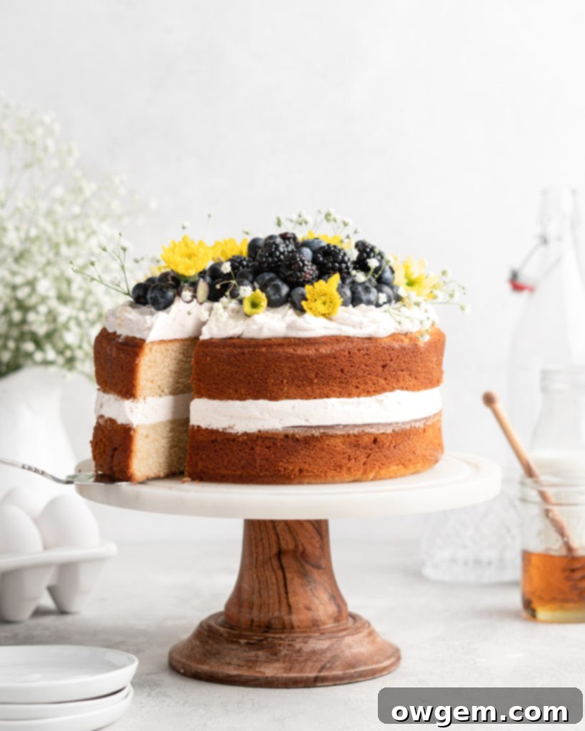 2 layer naked styled chamomile and honey infused cake is decorated with berries and flowers