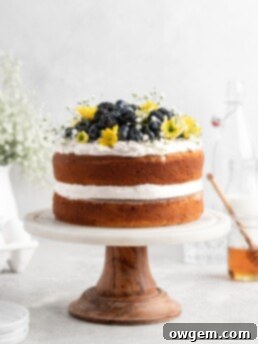 2 layer naked styled chamomile and honey infused cake is decorated with berries and flowers