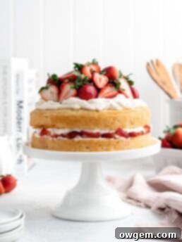 A beautifully assembled Strawberry Shortcake Layer Cake, showcasing its vibrant layers and fresh strawberry garnish
