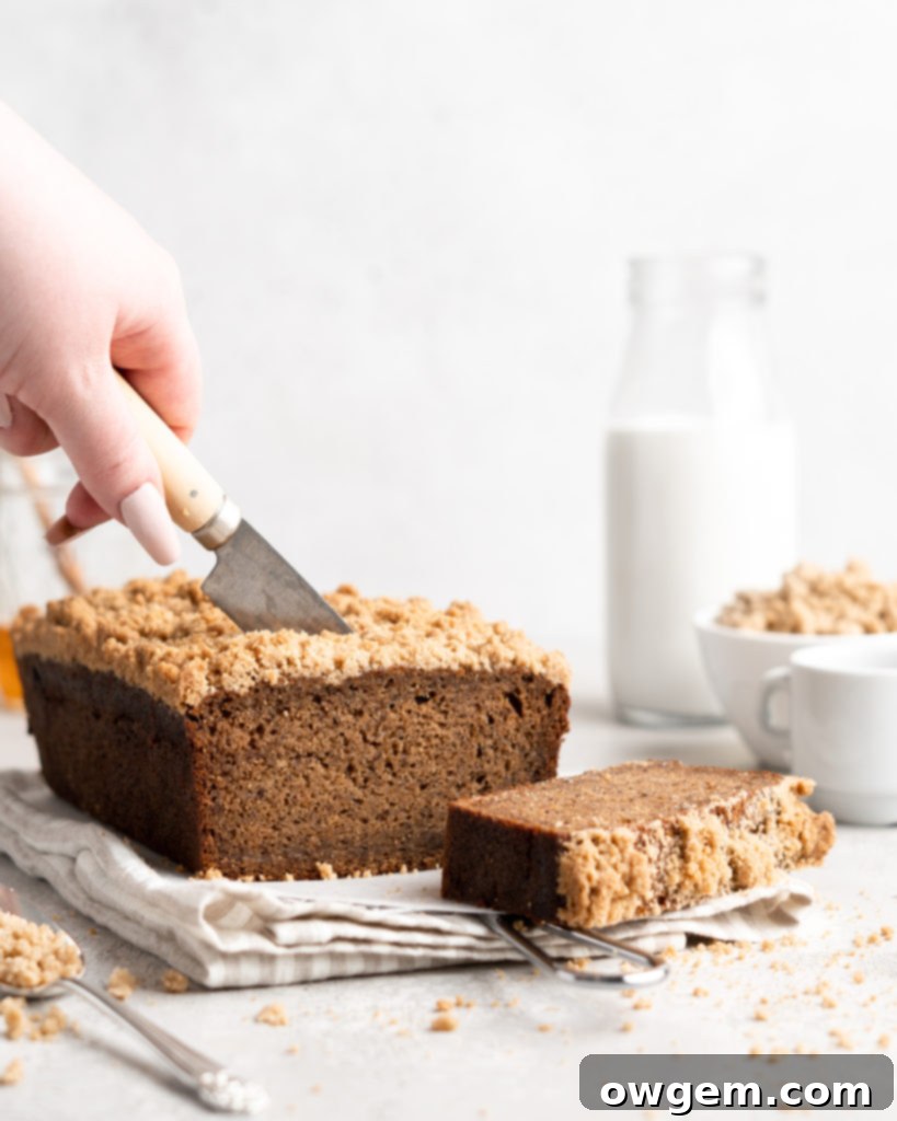 A perfectly baked slice of Chai Spiced Streusel Banana Bread on a white plate, showcasing its streusel topping and moist crumb.