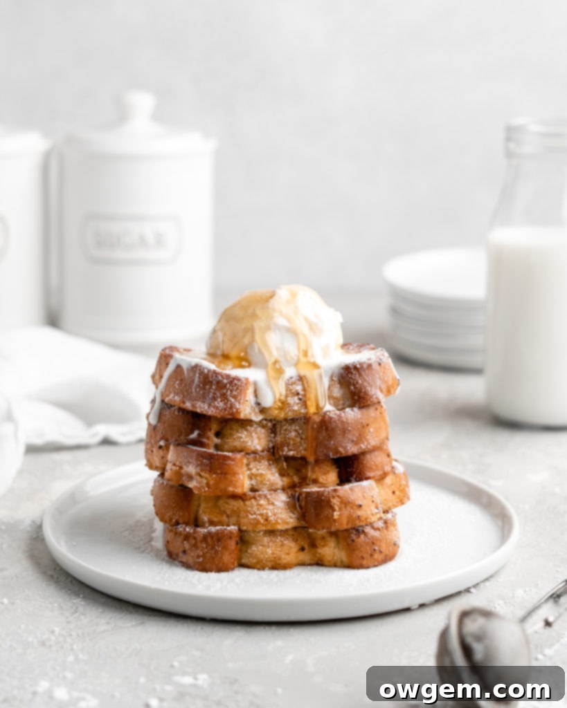 A stack of golden Buttermilk French Toast with Grand Marnier, dusted with powdered sugar and ready for toppings