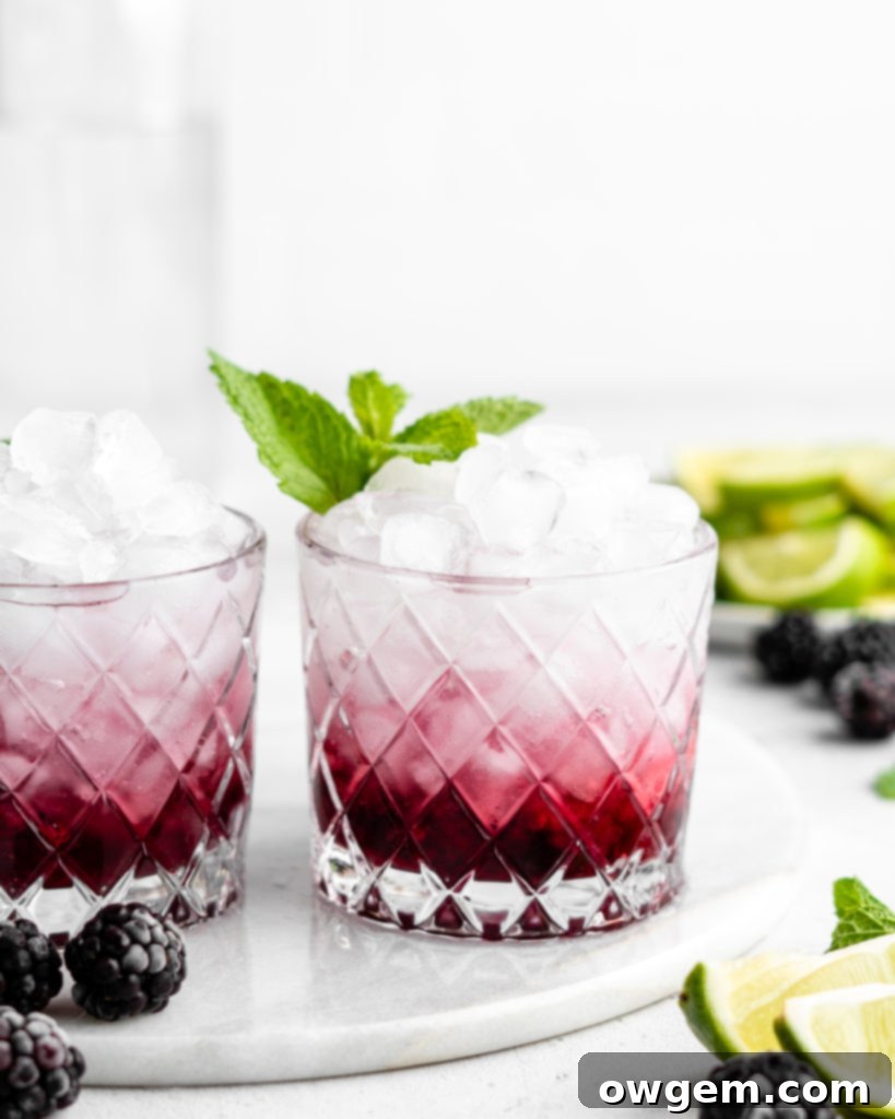 Hands gently slapping fresh mint leaves to release their aroma, with a blurred cocktail in the background.