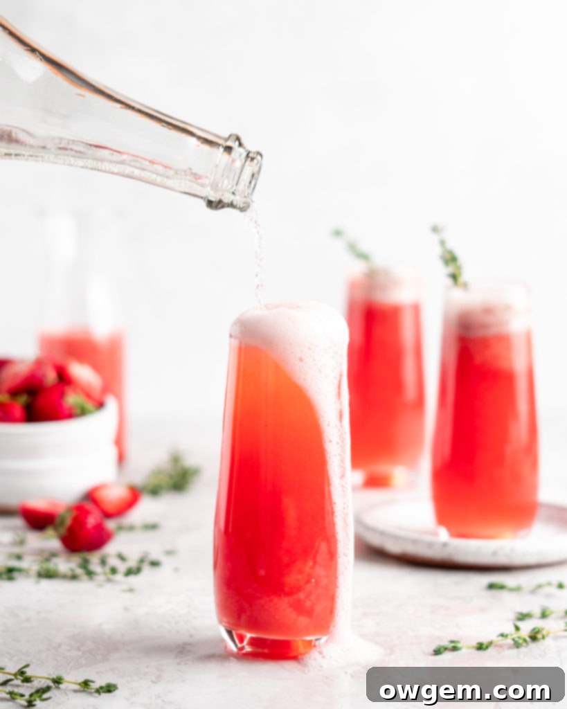 Bright red strawberry guava juice is mixed with sparkling rose wine in stemless champagne glasses to make Strawberry Guava Mimosa