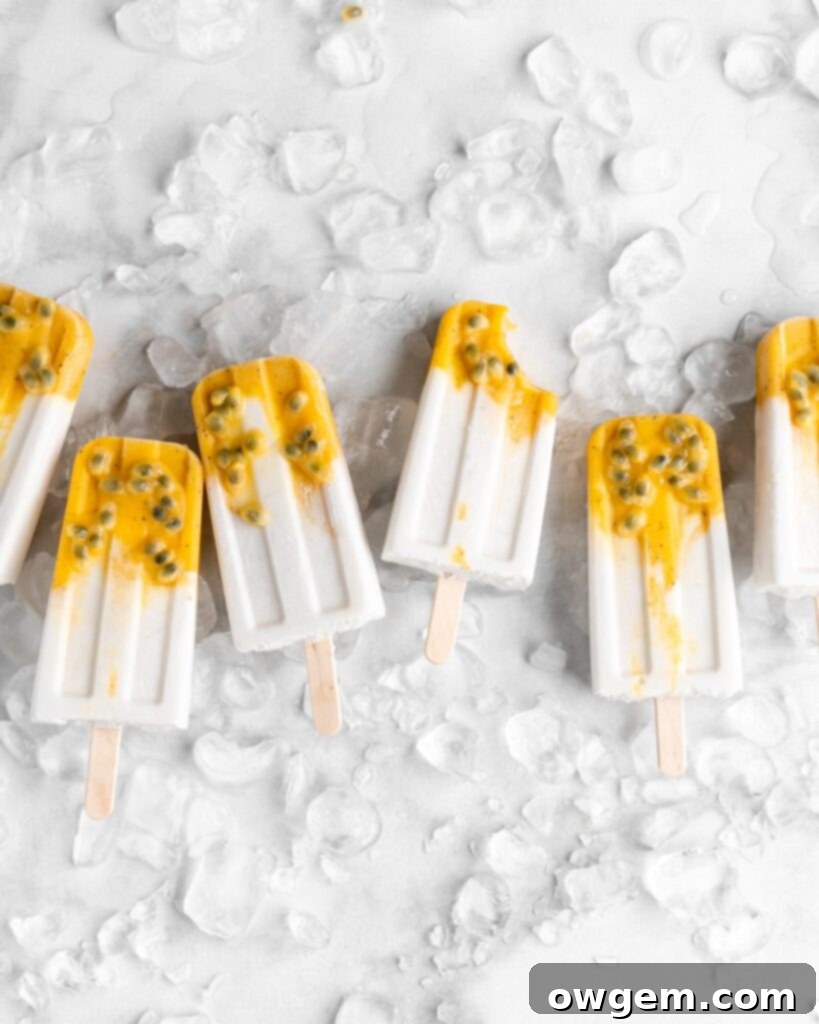 Tropical popsicles featuring mango, passion fruit, and coconut lay on a bed of ice