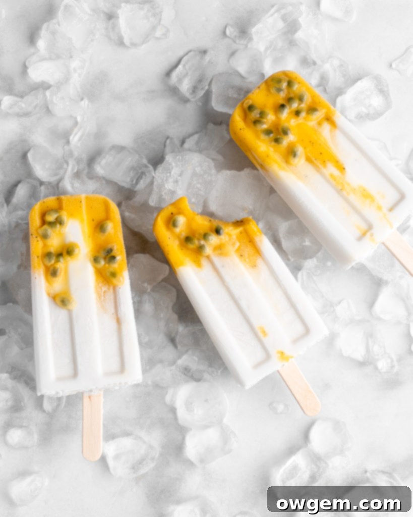 Tropical popsicles featuring mango, passion fruit, and coconut lay on a bed of ice