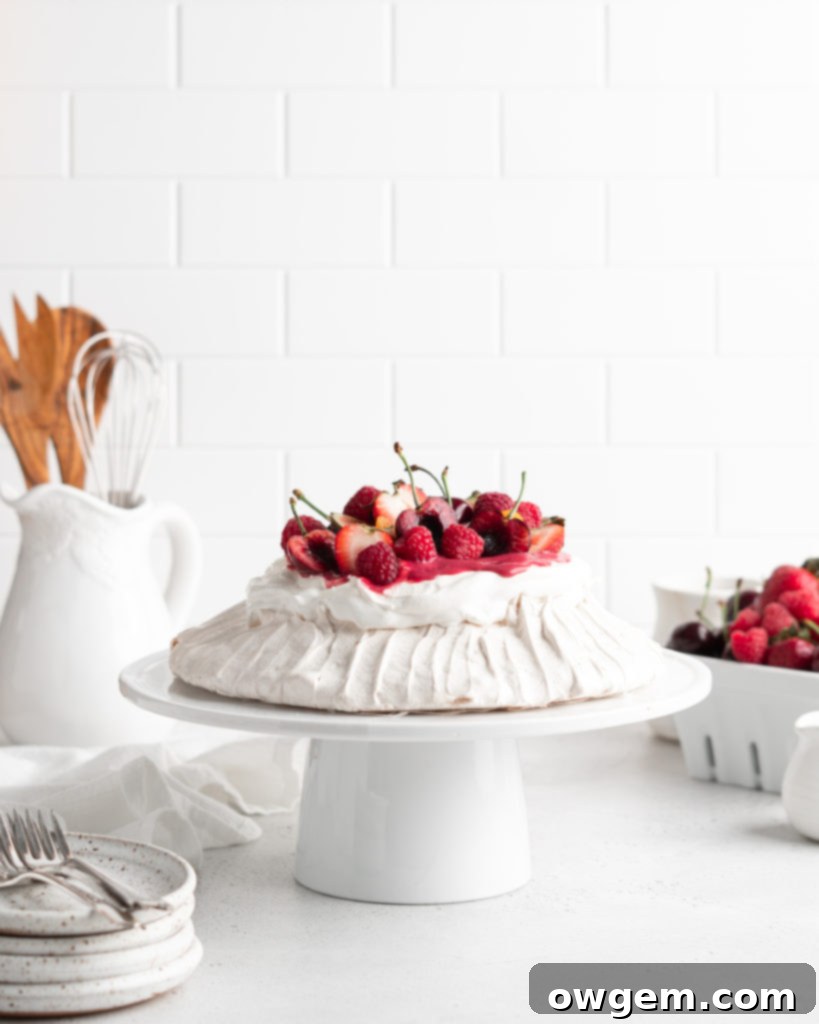 Close-up shot of a magnificent Summer Berry Pavlova, showing the crisp meringue, creamy whipped topping, and vibrant berries.