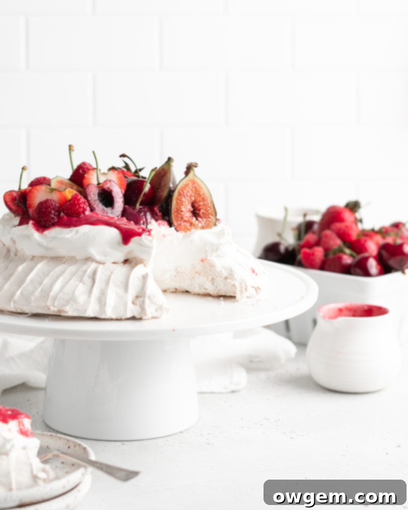 Side view of a freshly made Summer Berry Pavlova, showcasing its elegant height and colorful fruit toppings.