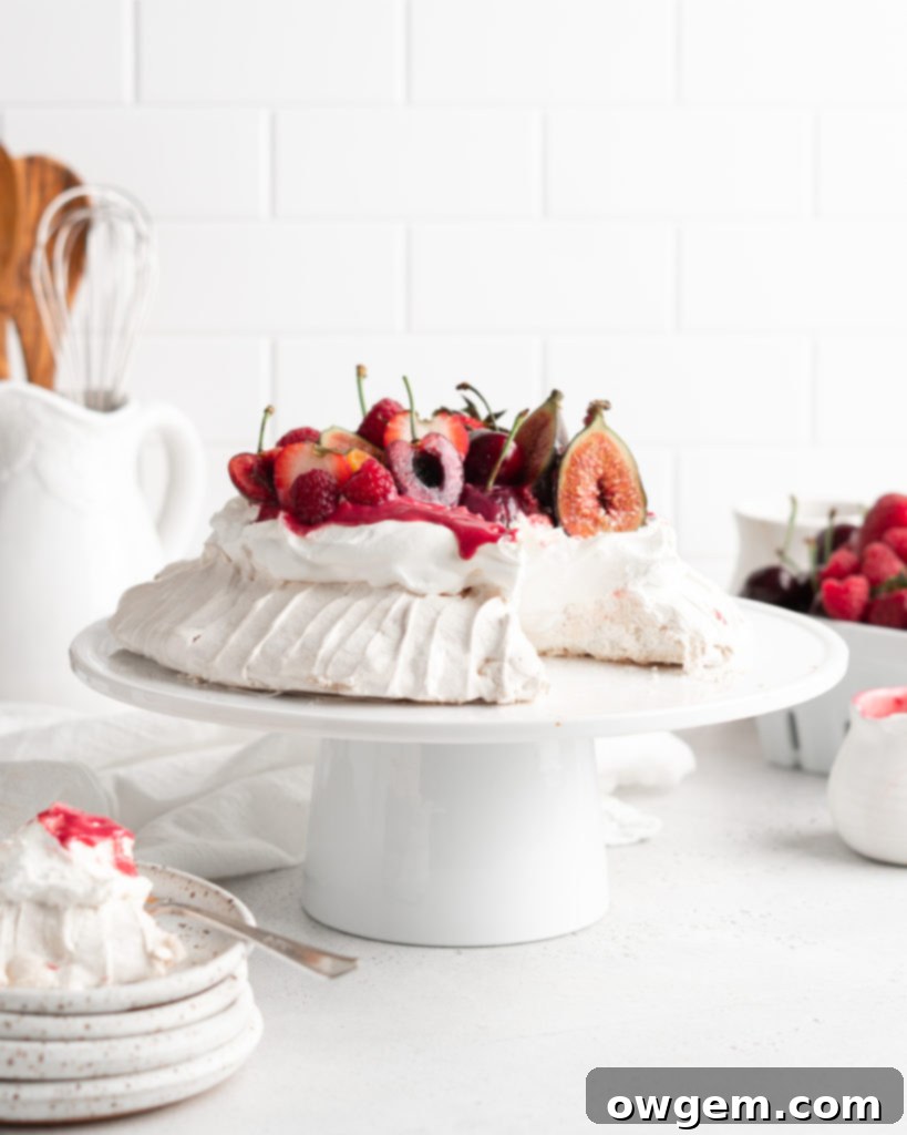 A vibrant raspberry curd being drizzled onto a Summer Berry Pavlova, showing its smooth texture and rich color.