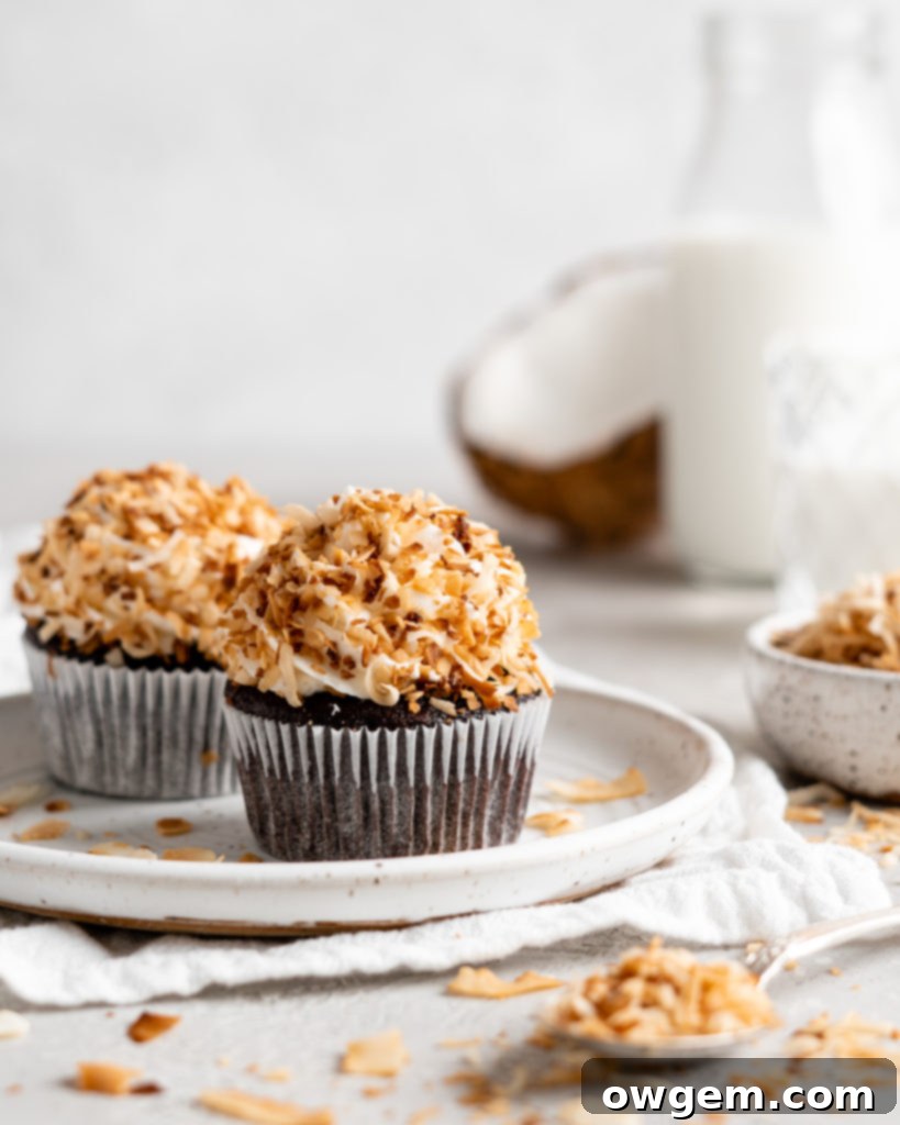 Two chocolate coconut cupcakes on a white plate, showcasing the frosting and toasted coconut