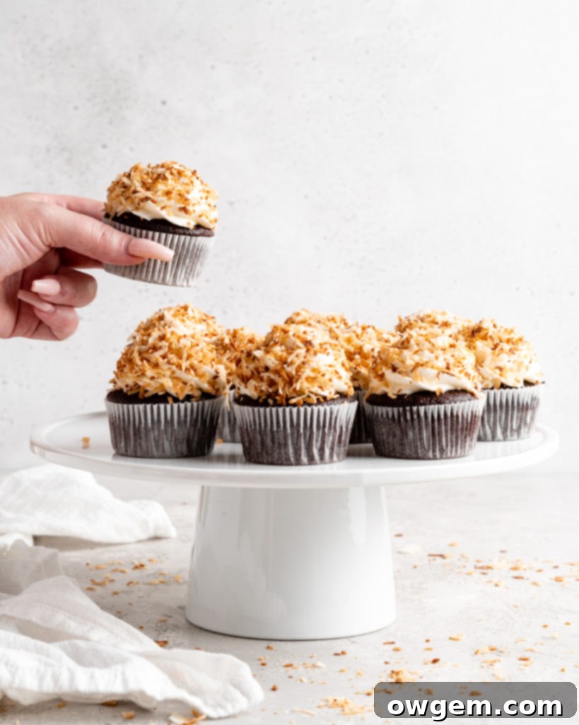 Finished chocolate coconut cupcakes on a cooling rack, garnished with toasted coconut
