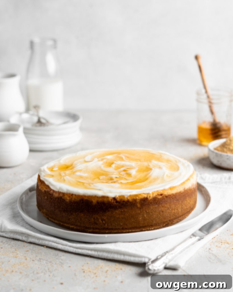 Creamy Salted Honey Cheesecake has a graham cracker crust and a sour cream topping. Drizzled with additional salted honey