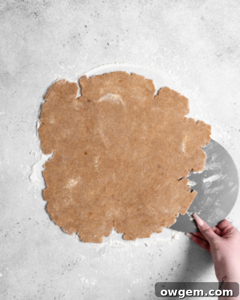 Carefully placing the tart pan bottom with pastry into the full tart ring.