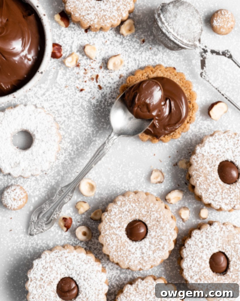 Flower shaped linzer cookies filled with nutella, sandwiched together, and dusted with confectioners sugar