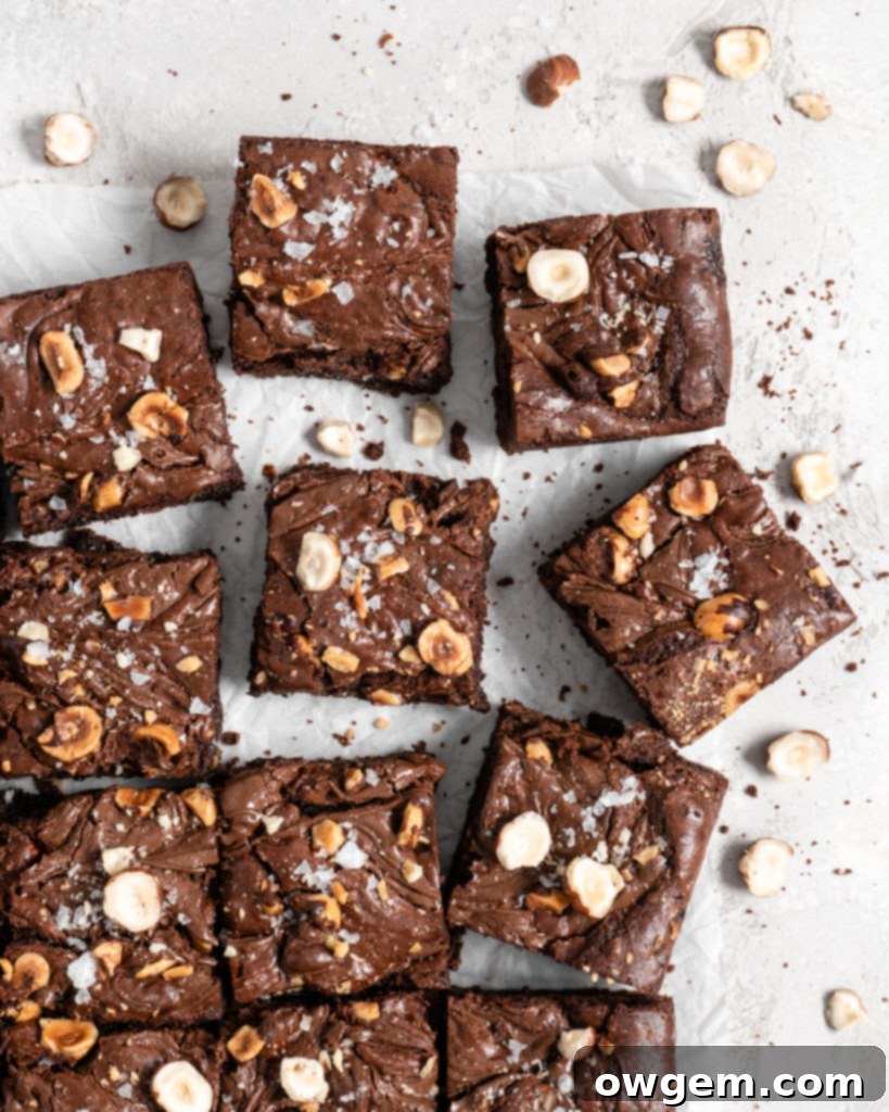 A stack of three rich chocolate brownies with toasted hazelnuts and Nutella swirls, ready to be served on a marble surface