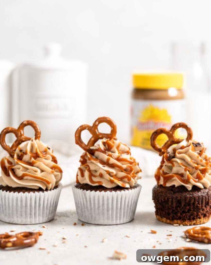 Decadent chocolate cupcake with a crunchy pretzel crust, topped generously with creamy SunButter buttercream frosting and a drizzle of salted caramel, presented beautifully on a white surface.